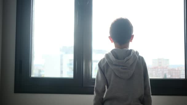 Вид Сзади Мальчика Капюшоне Выглядывающего Окна Городе — стоковое видео
