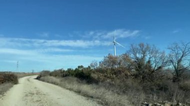 Kırsal bölgede araba kullanmak. Mavi gökyüzü arka planında rüzgar türbini 