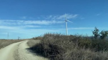 Kırsal bölgede araba kullanmak. Mavi gökyüzü arka planında rüzgar türbini 