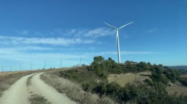 Kırsal bölgede araba kullanmak. Mavi gökyüzü arka planında rüzgar türbini 