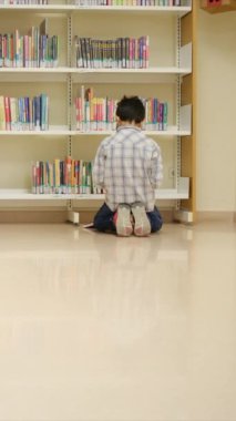 Okuldaki kütüphanedeki genç çocuk.