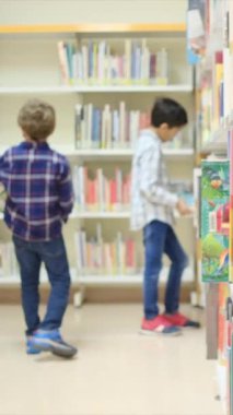 Küçük çocuklar kütüphanede kitap seçiyor.