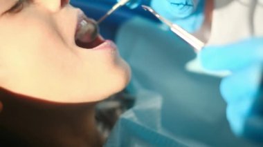 Diş hekimliği aletleriyle çocuğun dişlerini inceliyor. 