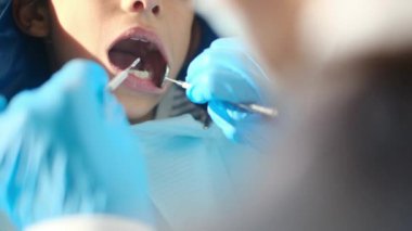 Diş hekimliği aletleriyle çocuğun dişlerini inceliyor. 