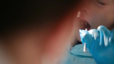 Diş hekimliği aletleriyle çocuğun dişlerini inceliyor. 
