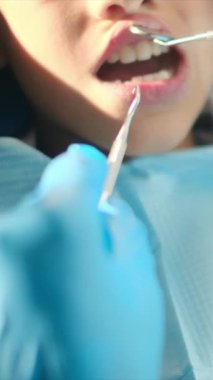 Diş hekimliği aletleriyle çocuğun dişlerini inceliyor. 