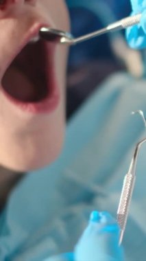 Diş hekimliği aletleriyle çocuğun dişlerini inceliyor. 