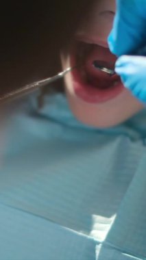 Diş hekimliği aletleriyle çocuğun dişlerini inceliyor. 