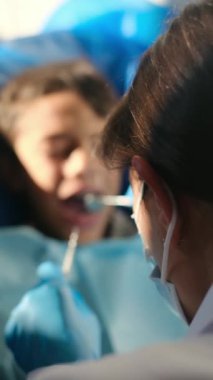 Diş hekimliği aletleriyle çocuğun dişlerini inceliyor. 
