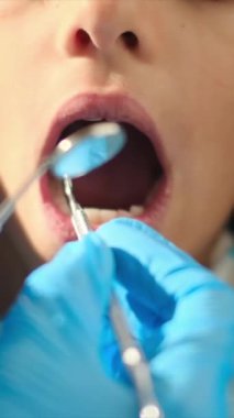 Diş hekimliği aletleriyle çocuğun dişlerini inceliyor. 