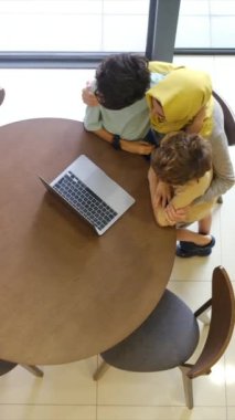tesettürlü Müslüman anne ve çocukları, 5 ve 8, samimi bir Ramazan bayramı görüntüsü için bir dizüstü bilgisayarla bağlanıyorlar, teknolojiyle aralarındaki mesafeleri eşitliyorlar.