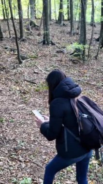 Ormanda akıllı telefonlu bir kadın doğa yürüyüşçüsü. 