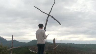 Dağlarda tahta haçların yanında dua eden bir kadın.