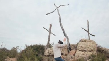 Dağlarda tahta haçların yanında dua eden bir kadın.