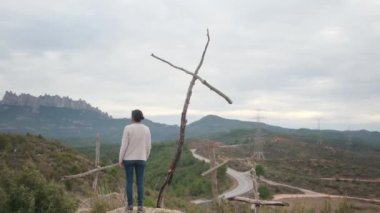 Dağlarda tahta haçların yanında dua eden bir kadın.