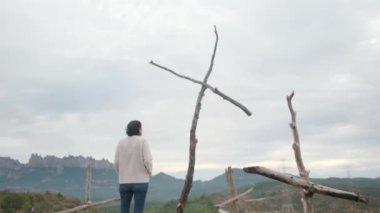 Dağlarda tahta haçların yanında dua eden bir kadın.