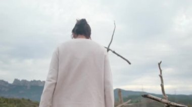 Dağlarda tahta haçın yanında dua eden bir kadın.