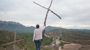 Dağlarda tahta haçların yanında dua eden bir kadın.