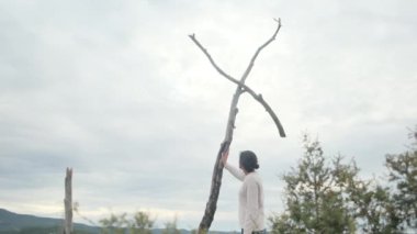Dağlarda tahta haçın yanında dua eden bir kadın.