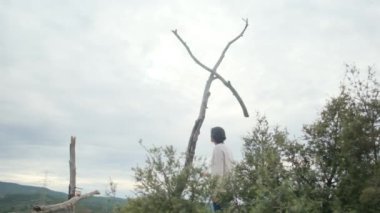 Dağlarda tahta haçın yanında dua eden bir kadın.