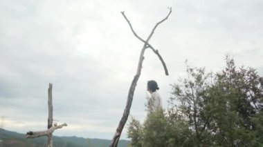 Dağlarda tahta haçın yanında dua eden bir kadın.