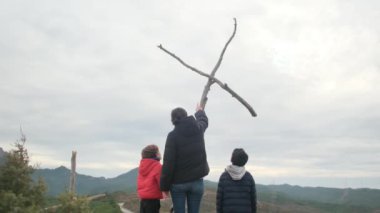 Anne dağın tepesindeki büyük bir haçın önünde birlikte dua ediyor. Hıristiyan inançlı aile ve anne Hıristiyanlık değerleri, dini inançlar, inanç ve umut öğretiyor. Farkındalık