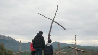 Dağlarda ahşap haçlar yakınında bir aile.