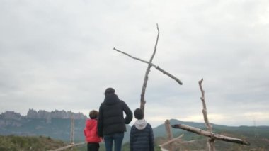 Dağlarda ahşap haçlar yakınında bir aile.