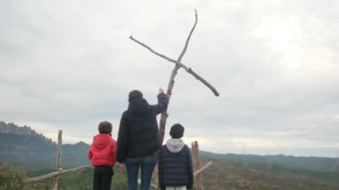 Anne dağın tepesindeki büyük bir haçın önünde birlikte dua ediyor. Hıristiyan inançlı aile ve anne Hıristiyanlık değerleri, dini inançlar, inanç ve umut öğretiyor. Farkındalık