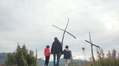 Dağlarda ahşap haçlar yakınında bir aile.