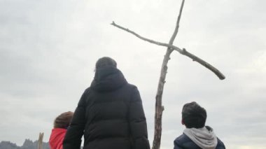 Annem, dağların tepesindeki büyük bir haçın önünde birlikte dua ediyor.