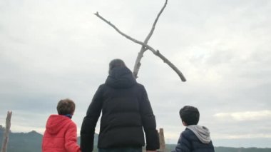 Anne dağın tepesindeki büyük bir haçın önünde birlikte dua ediyor. Hıristiyan inançlı aile ve anne Hıristiyanlık değerleri, dini inançlar, inanç ve umut öğretiyor. Farkındalık