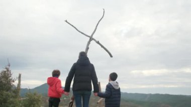 Anne dağın tepesindeki büyük bir haçın önünde birlikte dua ediyor. Hıristiyan inançlı aile ve anne Hıristiyanlık değerleri, dini inançlar, inanç ve umut öğretiyor. Farkındalık