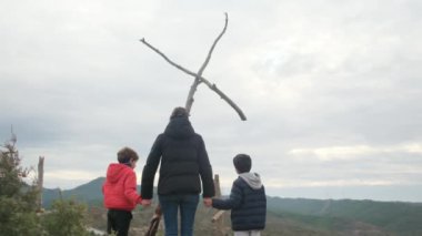 Anne dağın tepesindeki büyük bir haçın önünde birlikte dua ediyor. Hıristiyan inançlı aile ve anne Hıristiyanlık değerleri, dini inançlar, inanç ve umut öğretiyor. Farkındalık