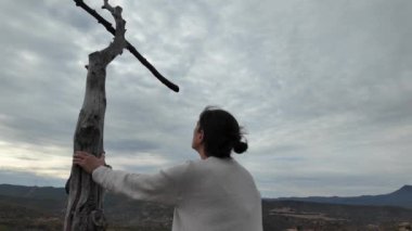 Dağlarda tahta haçın yanında dua eden bir kadın.