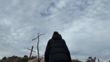 Dağlarda tahta haçların yanında dua eden bir kadın.
