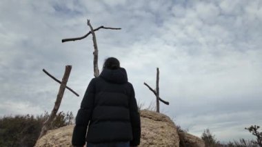 Dağlarda tahta haçların yanında dua eden bir kadın.