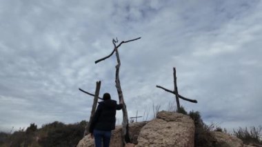 Dağlarda tahta haçların yanında dua eden bir kadın.