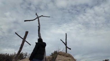 Dağlarda tahta haçların yanında dua eden bir kadın.