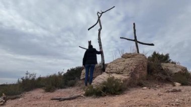 Dağlarda tahta haçların yanında dua eden bir kadın.