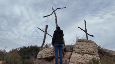 Dağlarda tahta haçların yanında dua eden bir kadın.