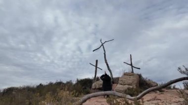 Dağlarda tahta haçların yanında dua eden bir kadın.