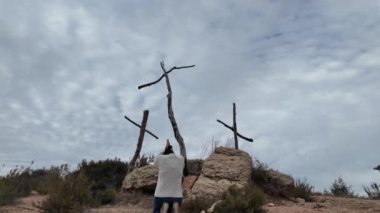Dağlarda tahta haçların yanında dua eden bir kadın.
