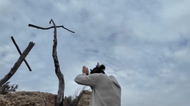 Dağlarda tahta haçların yanında dua eden bir kadın.