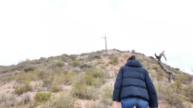 Dağlarda tahta haçın yanında bir kadın.