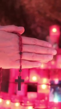 Bir insanın elleri, kilisede mumların önünde haçla dua eden bir kadın. Kavram, dua, umut, Tanrım, İsa Mesih. Din ve Tanrı 'ya olan umut ve inanç, farkındalık ve iç huzur.