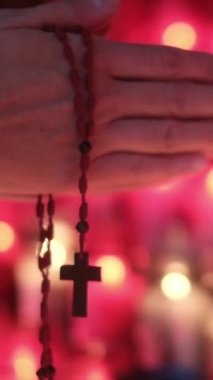 Bir insanın elleri, kilisede mumların önünde haçla dua eden bir kadın. Kavram, dua, umut, Tanrım, İsa Mesih. Din ve Tanrı 'ya olan umut ve inanç, farkındalık ve iç huzur.