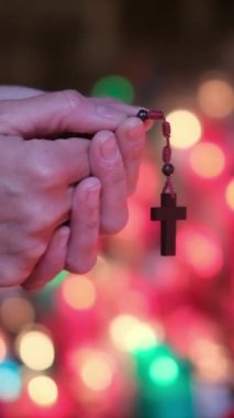 Bir insanın elleri, kilisede mumların önünde haçla dua eden bir kadın. Kavram, dua, umut, Tanrım, İsa Mesih. Din ve Tanrı 'ya olan umut ve inanç, farkındalık ve iç huzur.