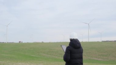 woman engineer with tablet  computer working in countryside with wind turbines