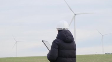 woman engineer with tablet  computer working in countryside with wind turbines
